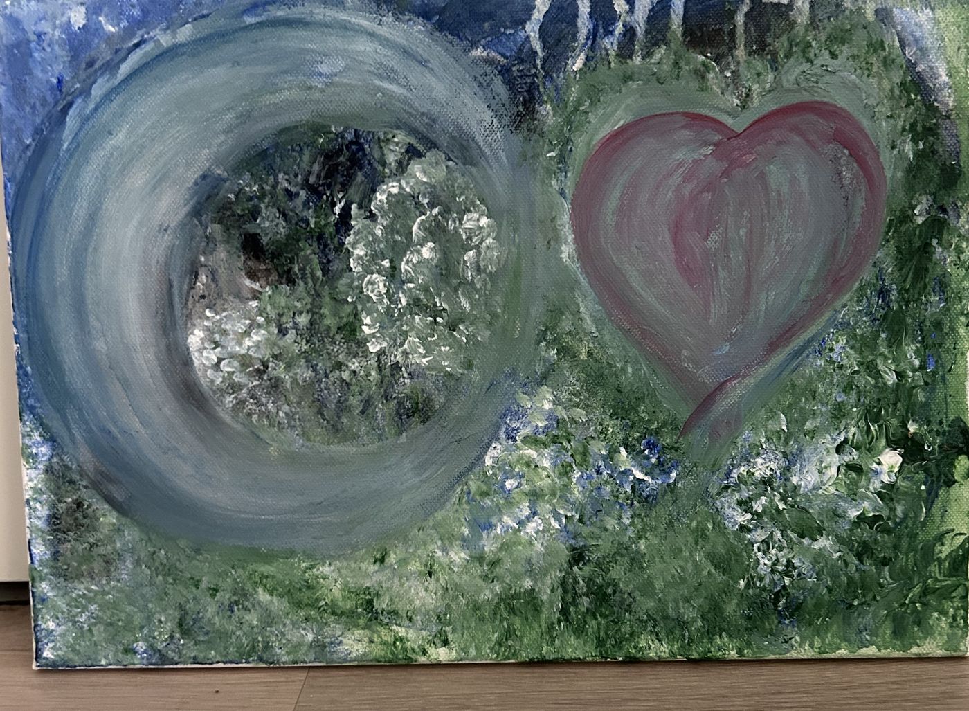 Målning med en grå cirkel och ett rosa hjärta mot grönt och blått